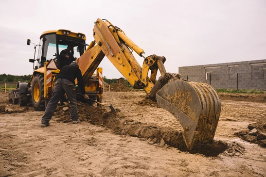 Excavateur travaillant sur le chantier de construction de maison - creusant les fondations d'une maison moderne