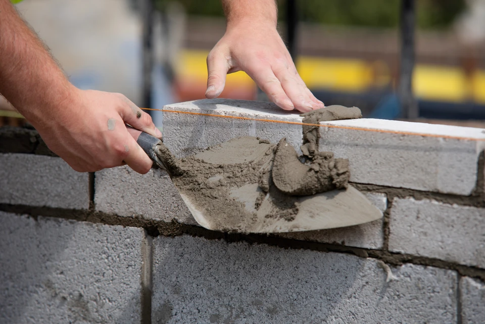 Chantier de construction en extérieur avec ouvriers en casques de sécurité travaillant sur dalle béton armé